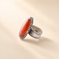 Silver Medieval statement ring with a large orange stone on a beige background