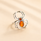 Silver spider amber ring with amber stones on a beige background