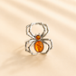 Silver spider-shaped amber ring with stones on a beige background