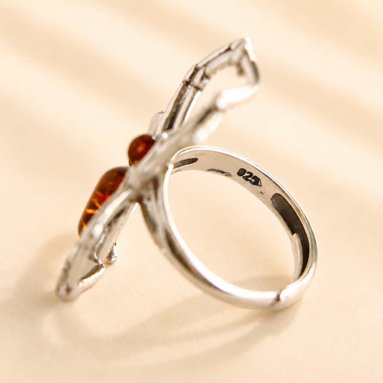 Silver amber ring with a Baltic amber stone on a beige background