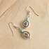 Silver western earrings with turquoise beads on a beige stone surface
