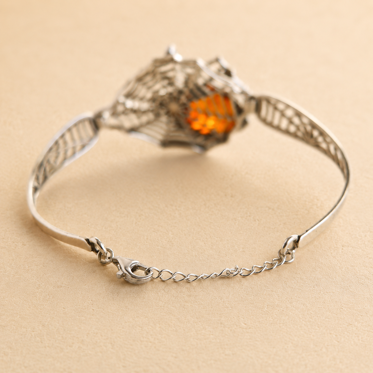 Silver amber bracelet with a heart-shaped orange gemstone on a beige background