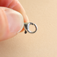 Close-up of a silver clasp held between fingers on a beige background for amber bracelet