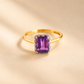 Gold Solitaire ring with a purple gemstone on a beige background