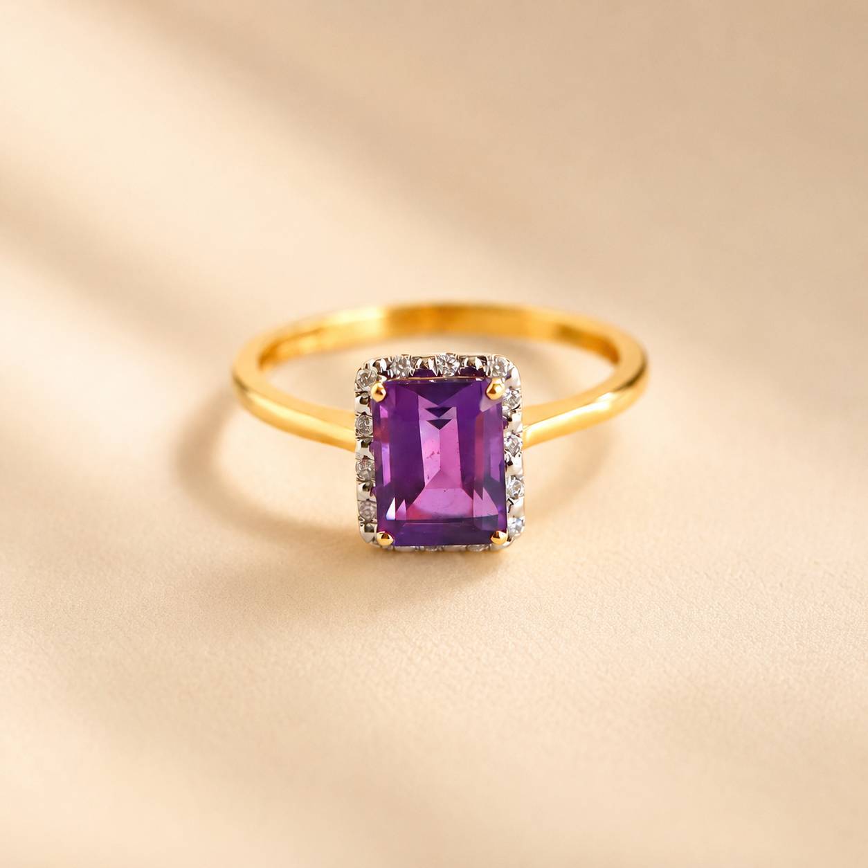 Gold Solitaire ring with a purple gemstone on a beige background