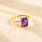 Gold Solitaire ring with a purple gemstone on a beige background