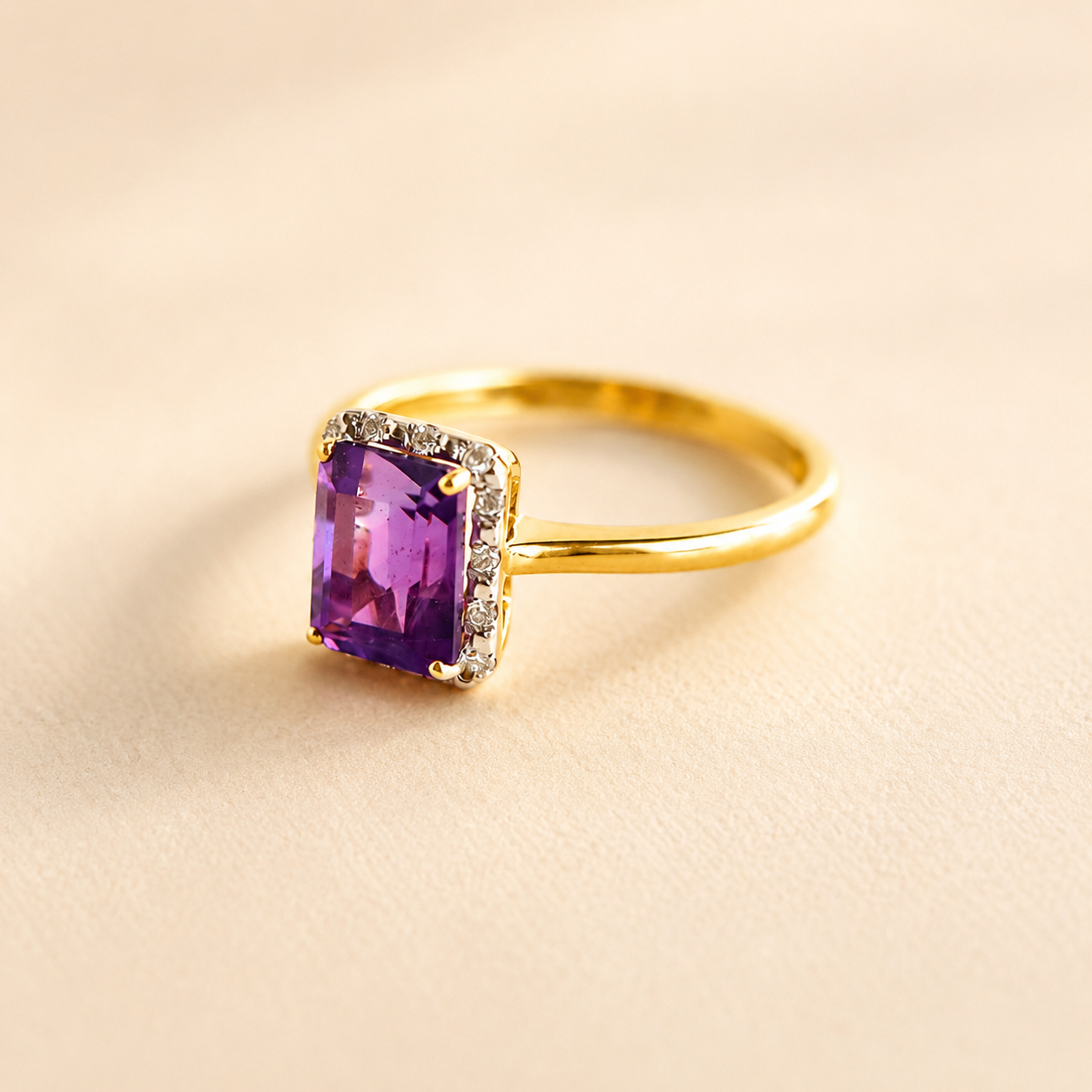 Gold Solitaire ring with a purple gemstone on a beige background