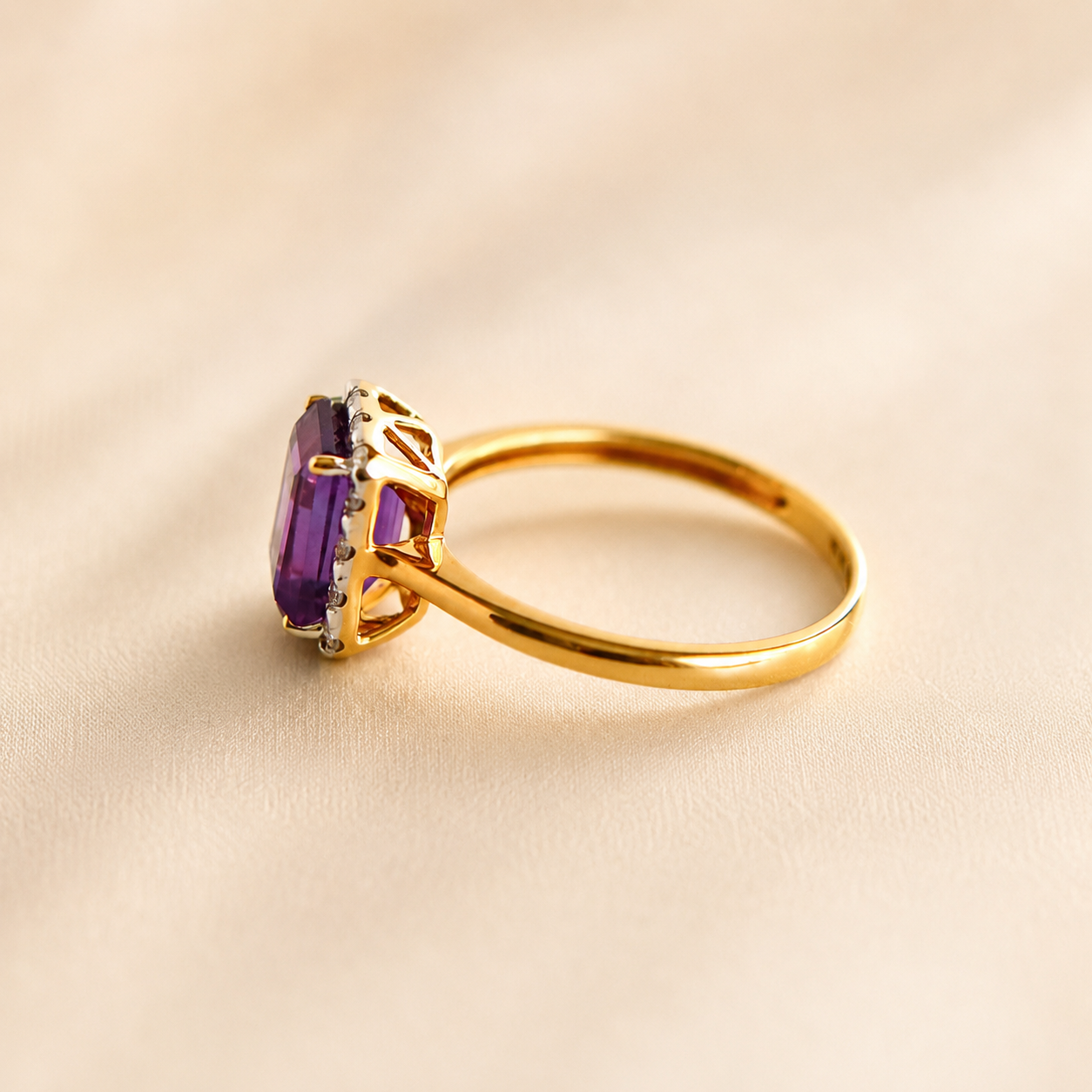 Gold Solitaire ring with a purple gemstone on a beige background