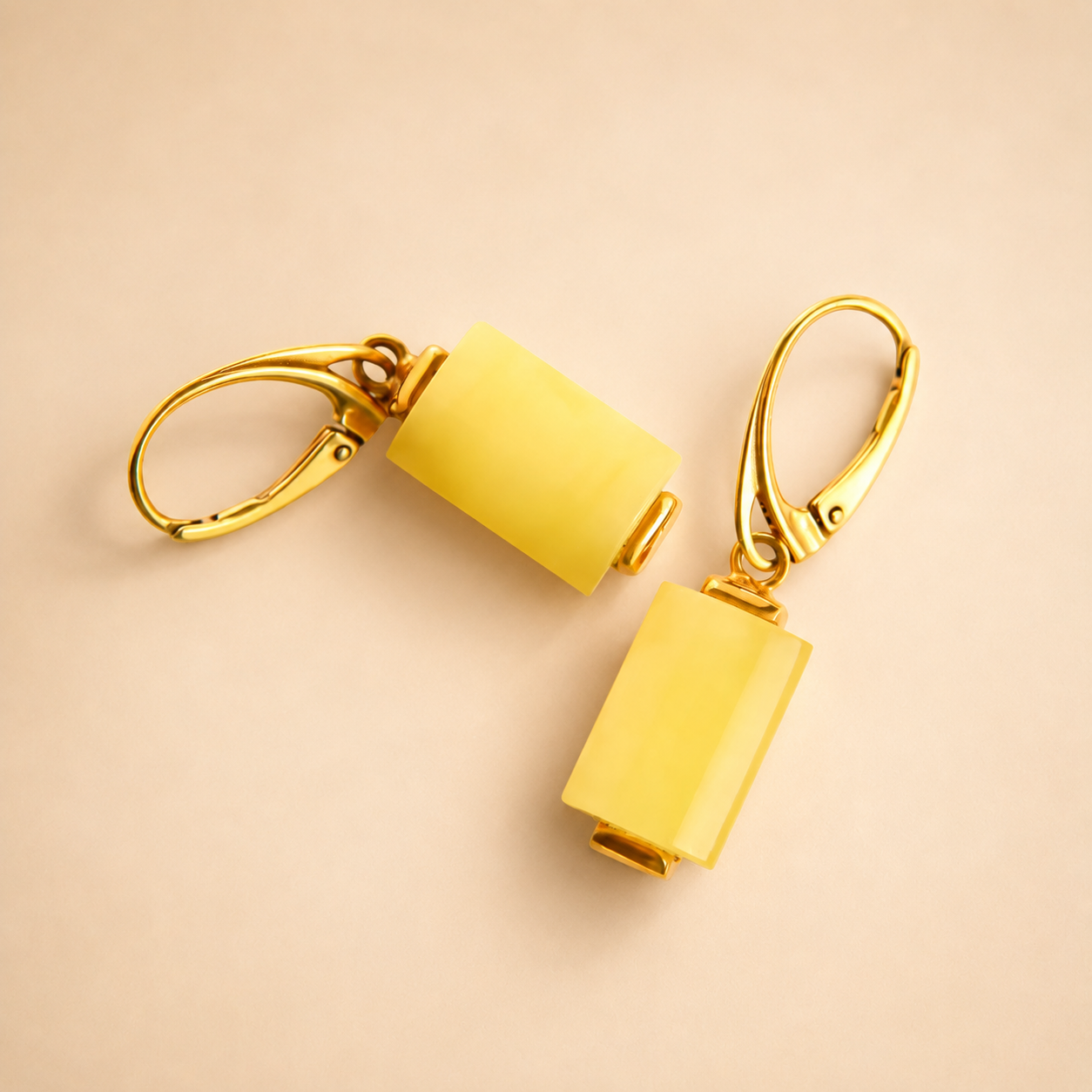 butterscotch amber earrings with gold hooks on a beige background