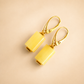 butterscotch amber earrings with gold hooks on a beige background