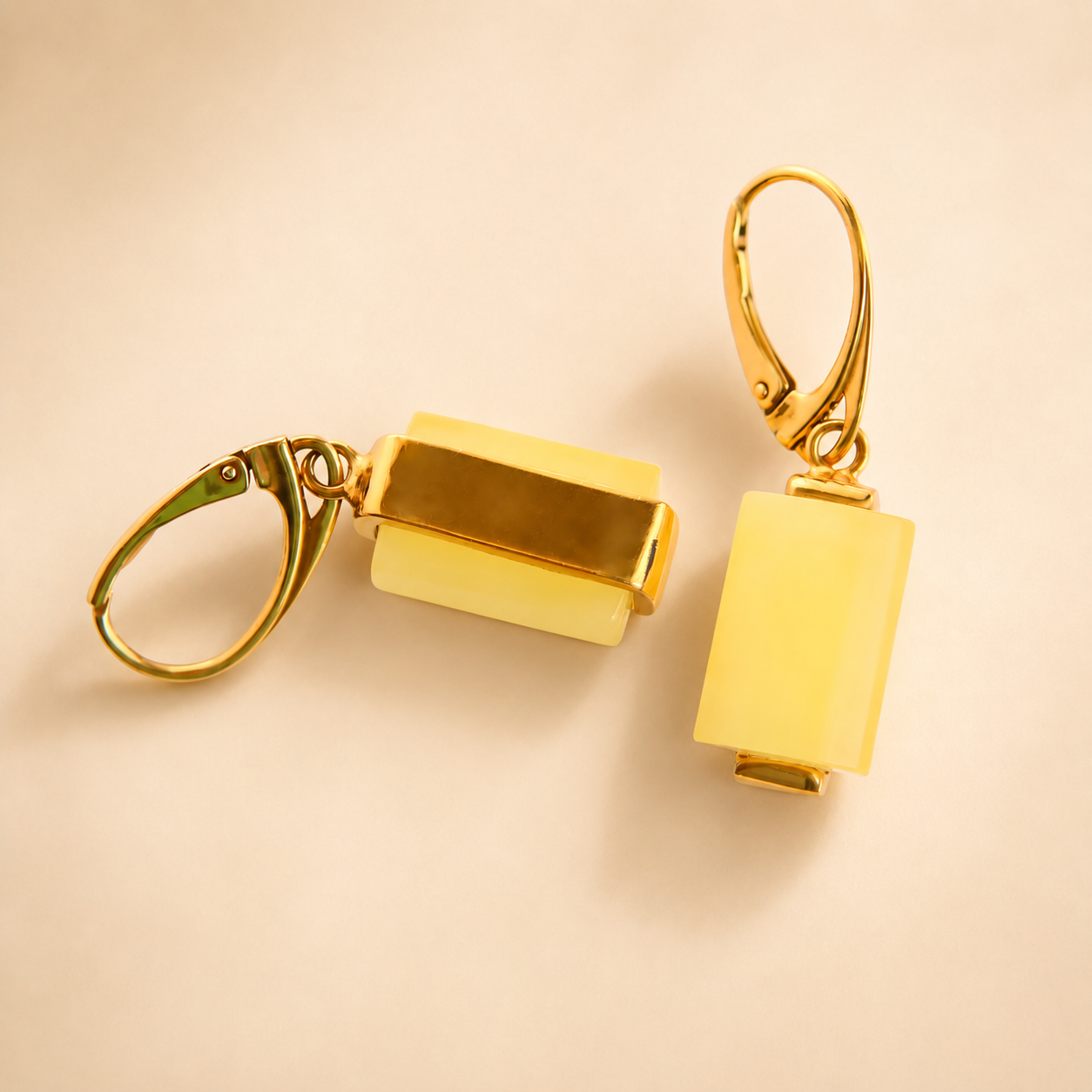 Gold rectangular butterscotch amber earrings on a beige background