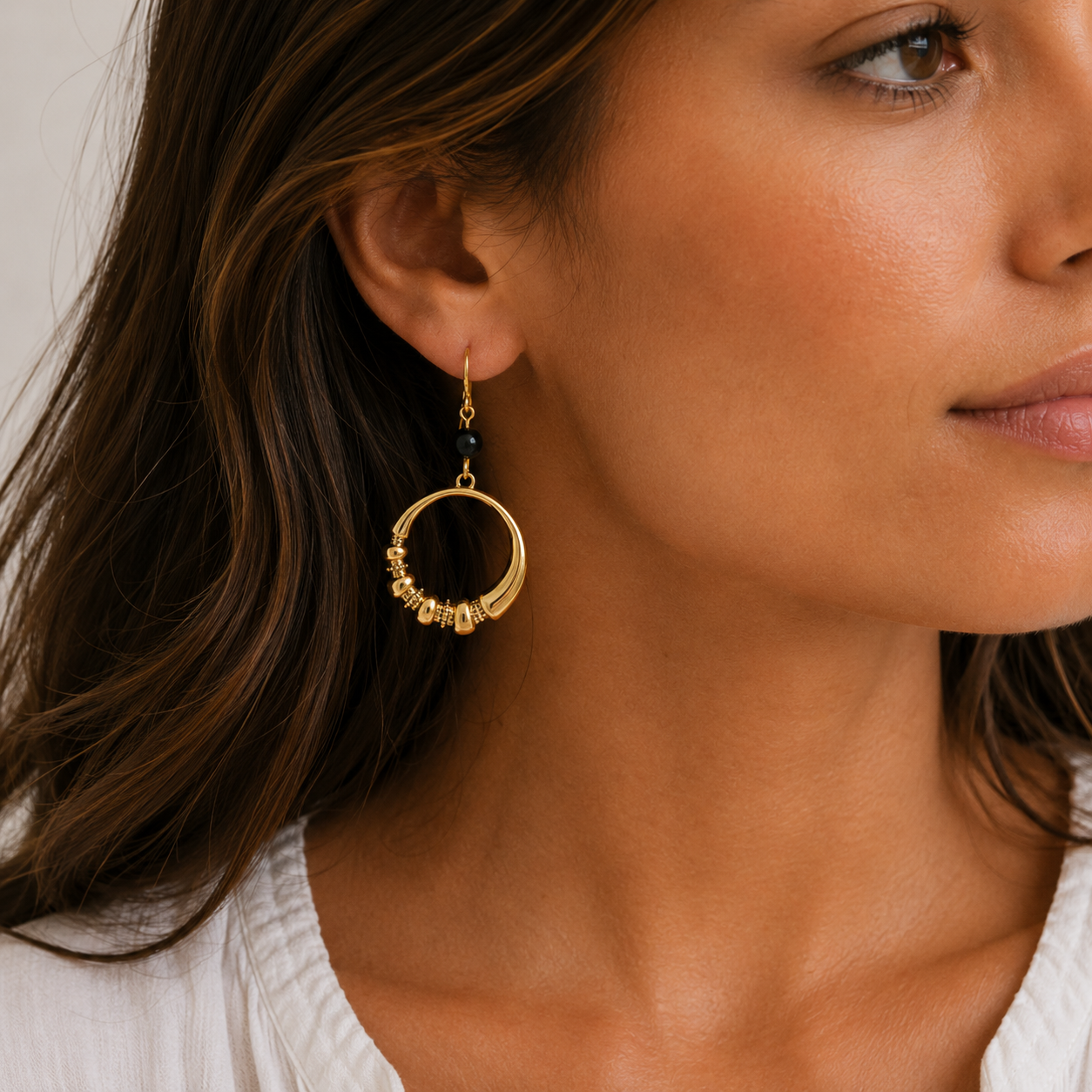 gold hoop earrings on model with light background