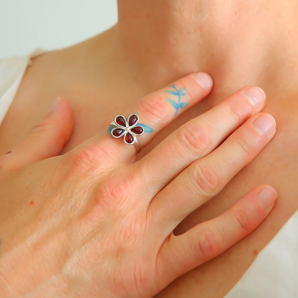 Silver ring with a floral design on a person's finger