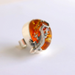 Statement ring with amber and silver lizard design on a white background