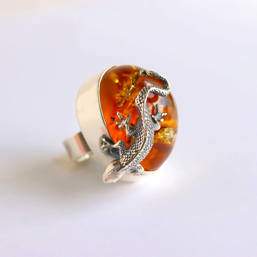 Statement ring with amber and silver lizard design on a white background