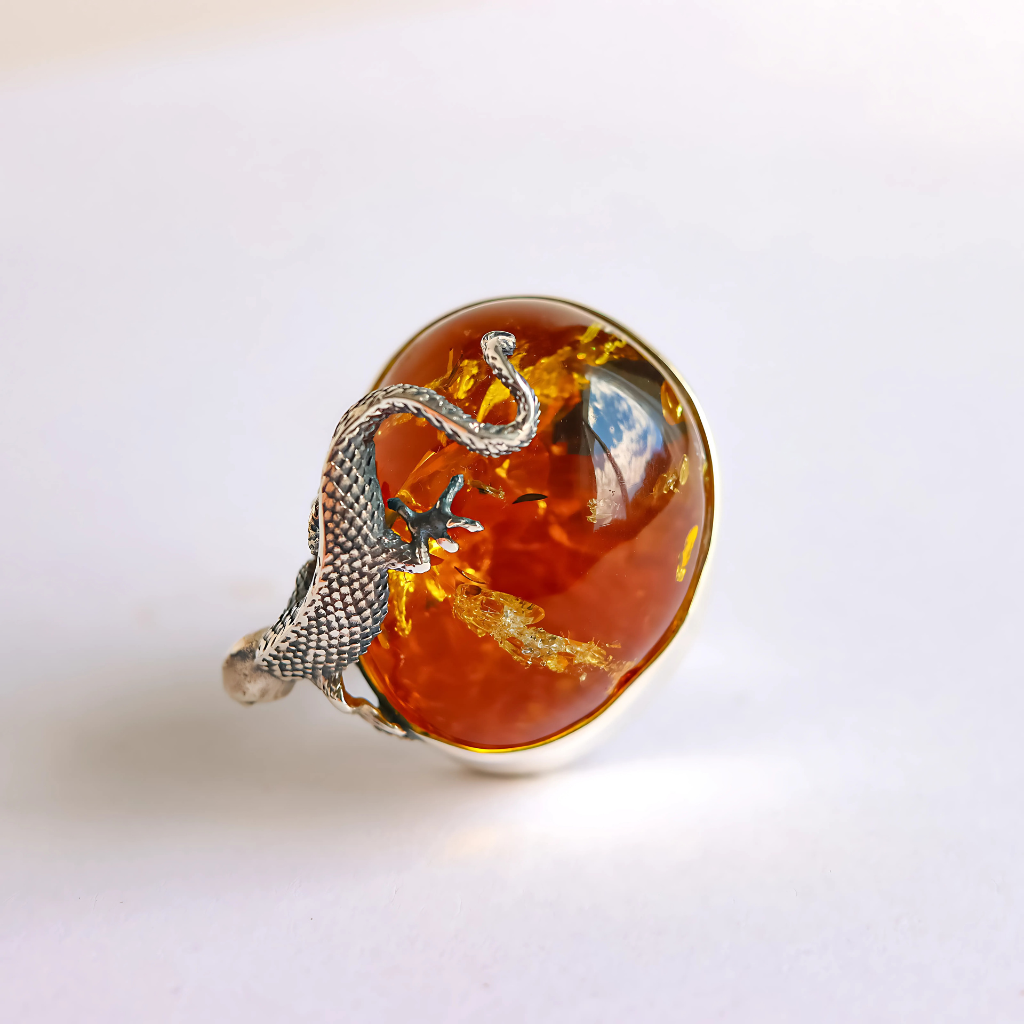 Silver statement ring with an amber stone on a white background
