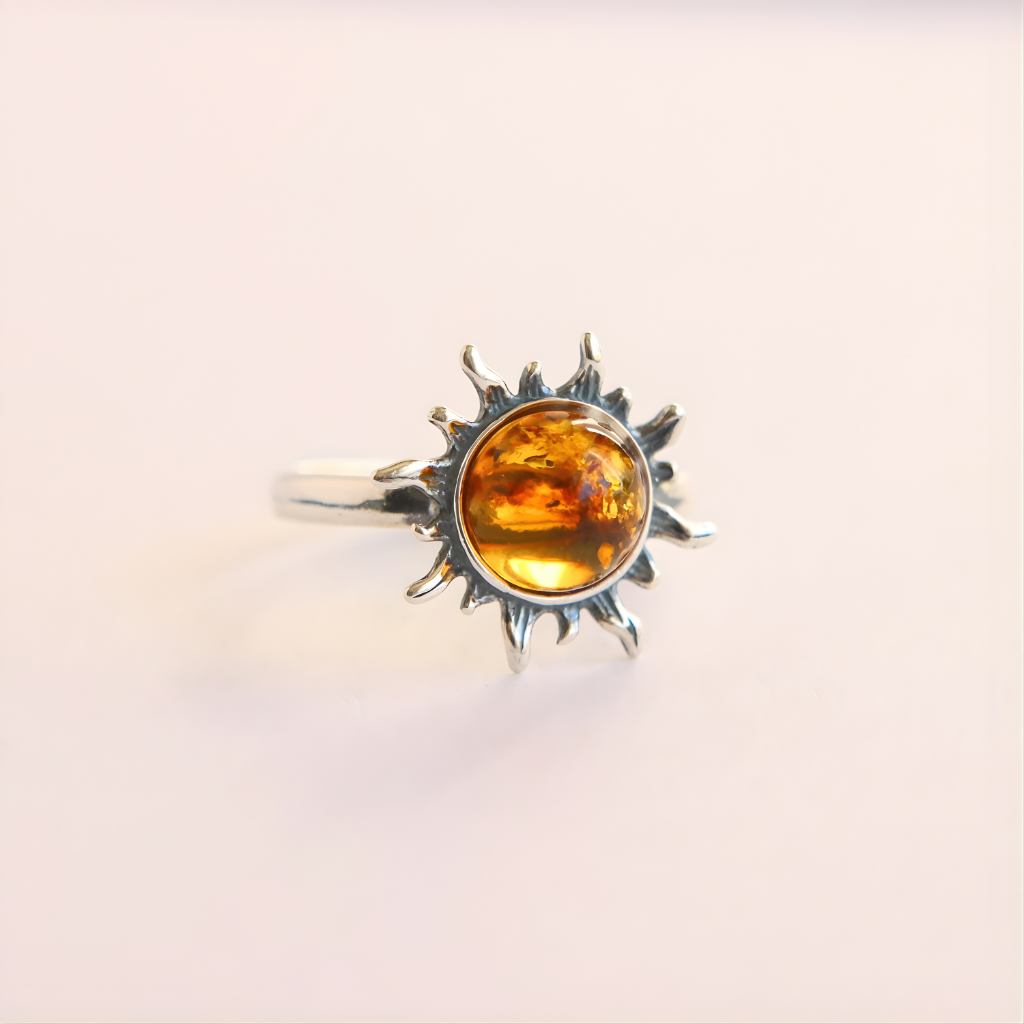 Silver amber ring with a sun design and amber stone on a light beige background
