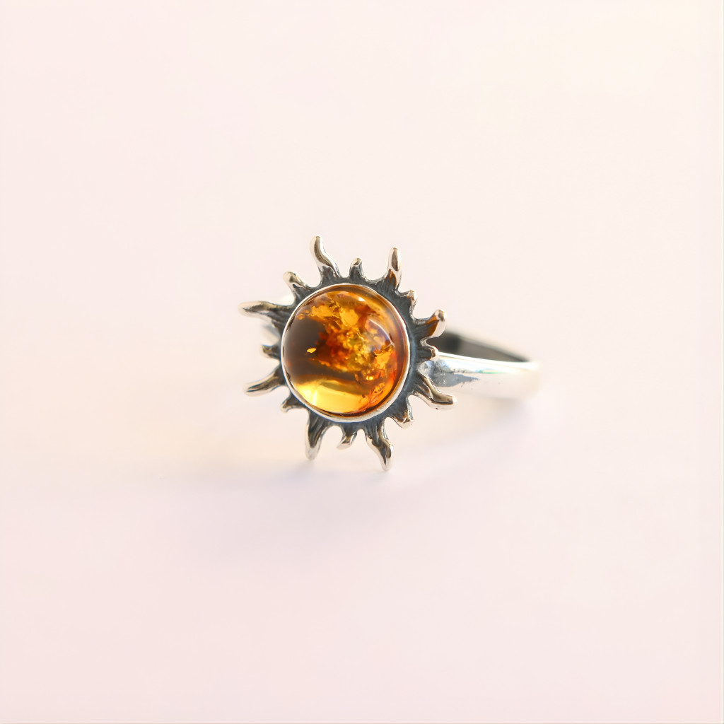 Silver amber ring with a sun design and amber stone on a light background