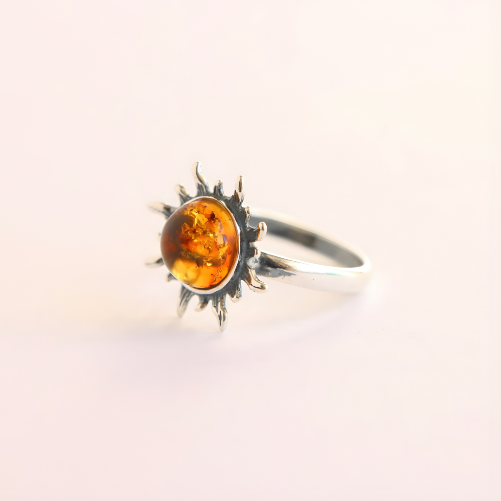 Silver amber ring with a sun design and amber stone on a light background