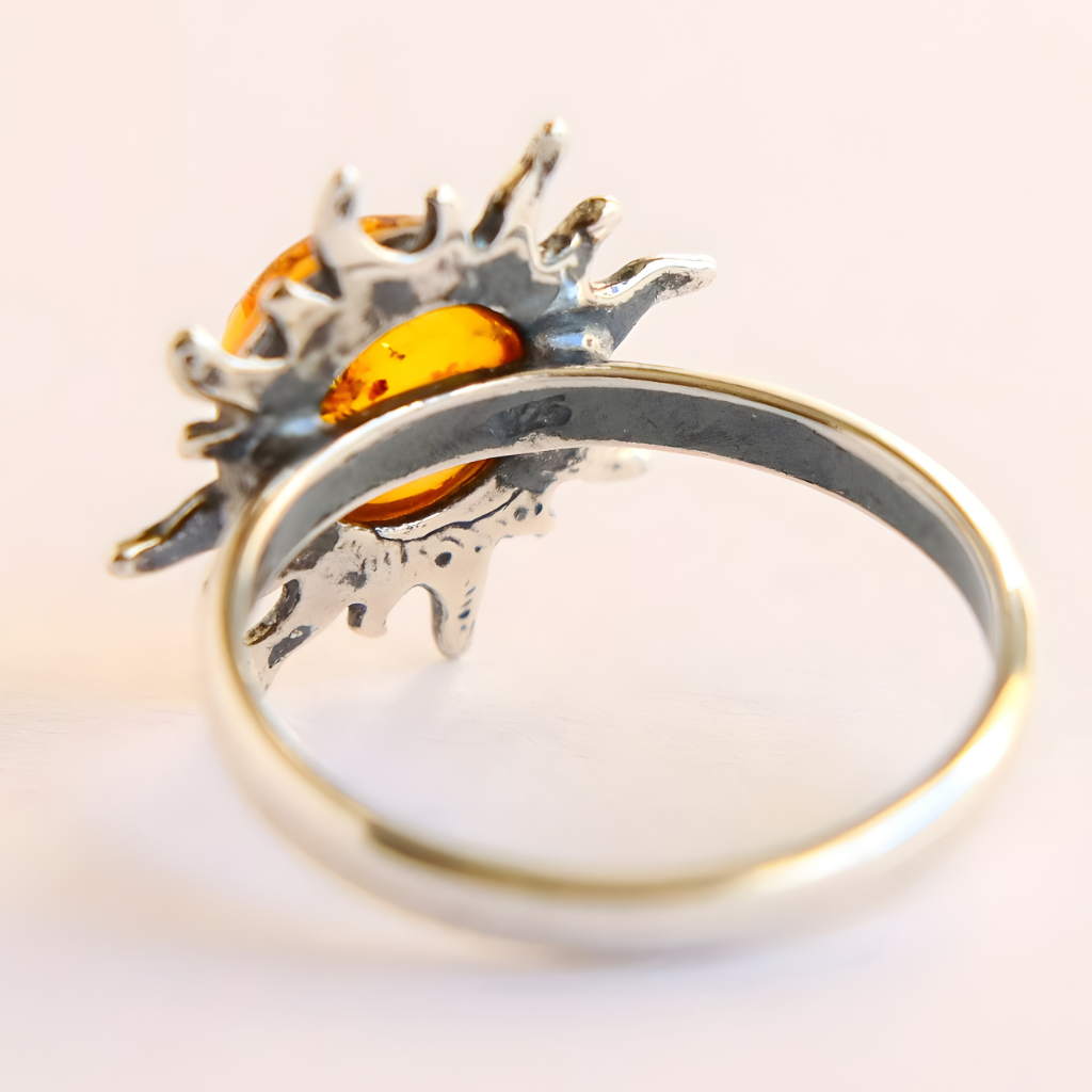 Silver amber ring with a sun design and amber stone on a light background