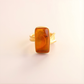 Gold amber ring with a large amber stone on a light beige background