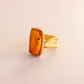 Gold amber ring with amber stone on a beige background