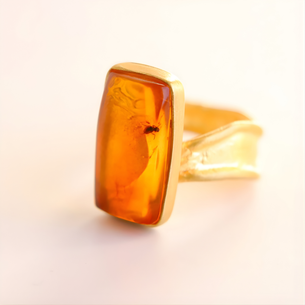 Gold amber ring with a large amber stone on a light background