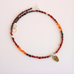 Amber beaded necklace laid flat showing full strand length, multicolor Baltic amber beads, skull charm, and toggle closure.