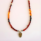 Close-up of Day of the Dead skull pendant on amber beaded necklace with silver flower spacer beads.