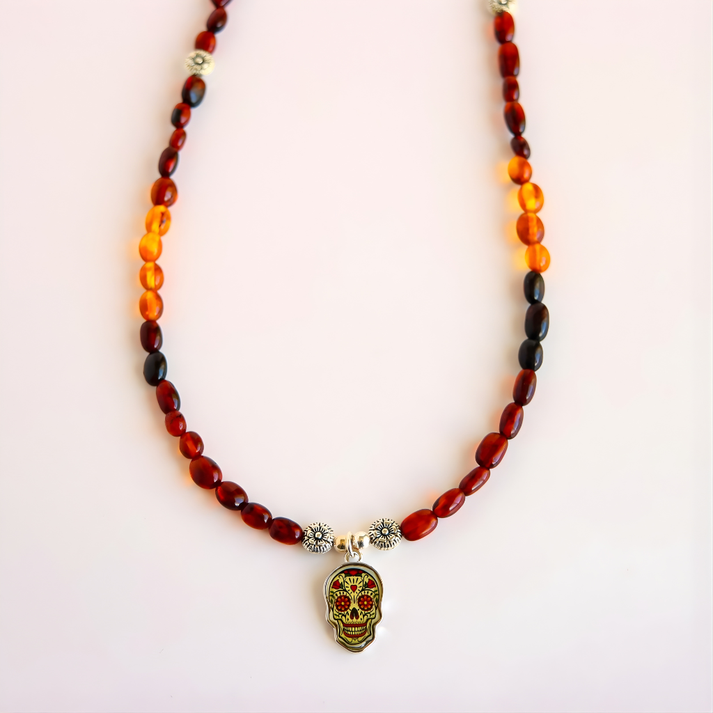 Close-up of Day of the Dead skull pendant on amber beaded necklace with silver flower spacer beads.