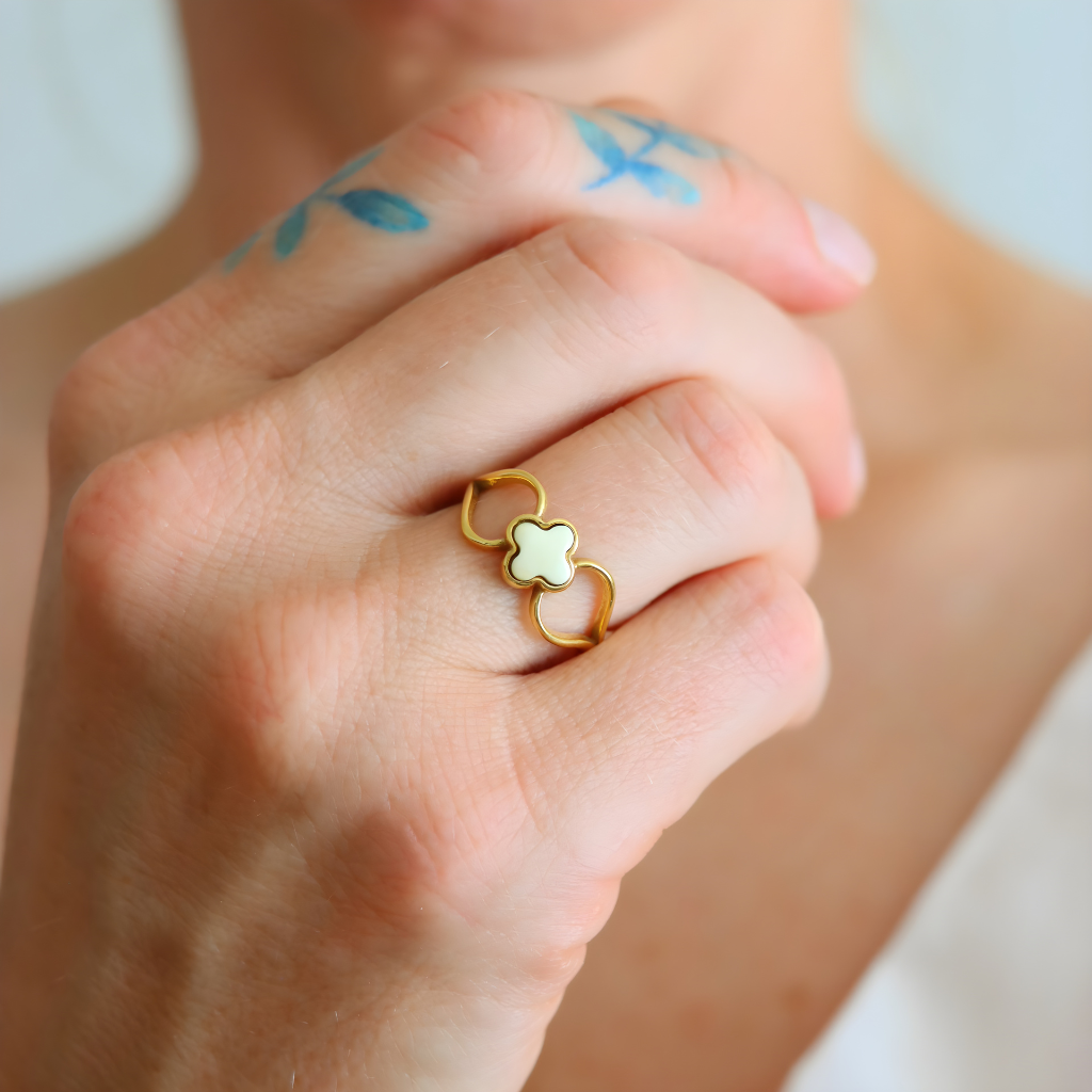 Close-up of a hand wearing a gold amber ring with a four leaf clover center.