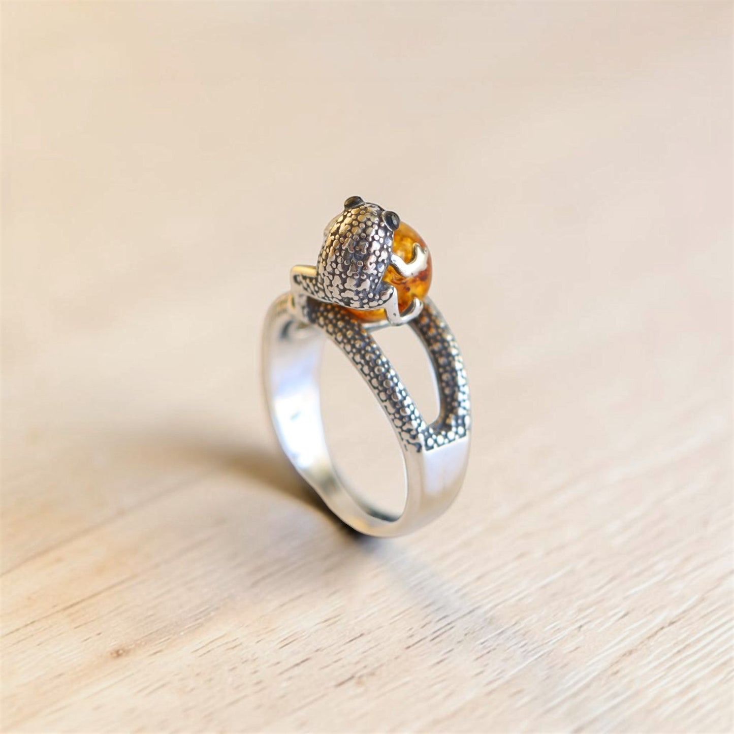 Back view of sterling silver frog ring showing textured frog detail, amber cabochon, and adjustable band.