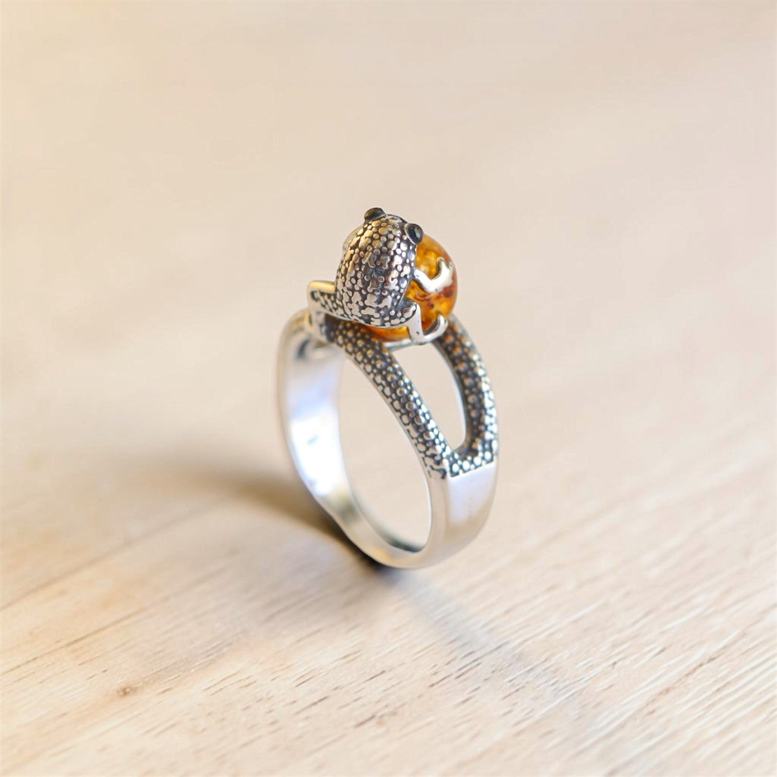 Back view of sterling silver frog ring showing textured frog detail, amber cabochon, and adjustable band.