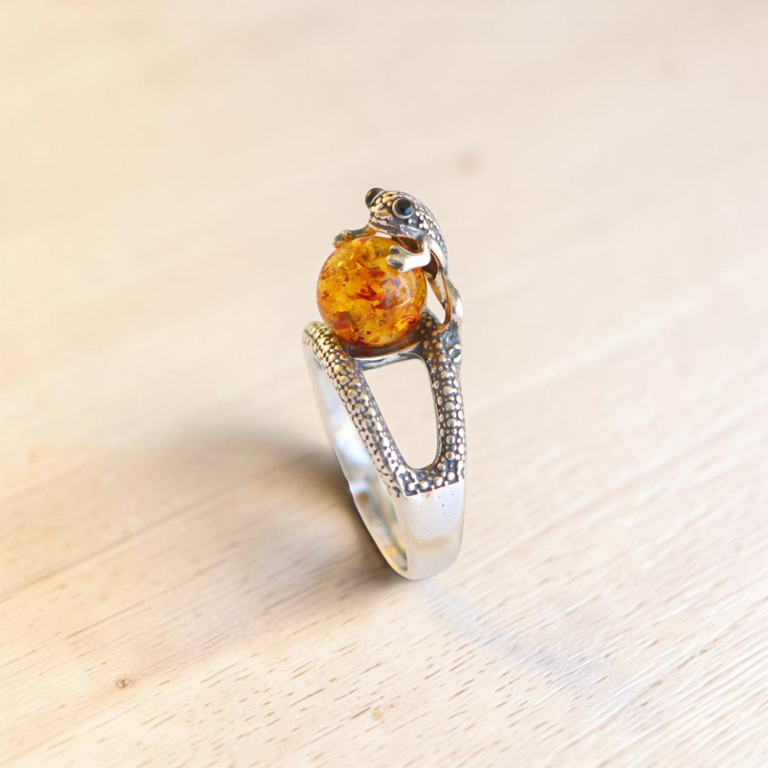 Side view of sterling silver frog ring with Baltic amber cabochon and textured open band.