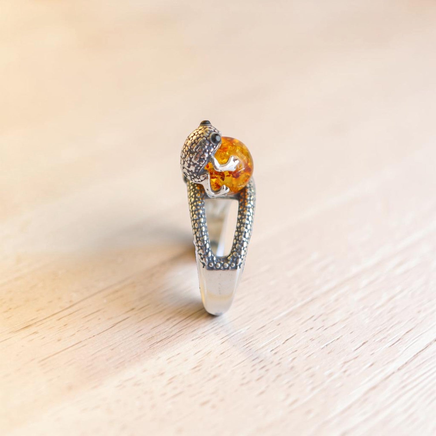 Side view of sterling silver frog ring with Baltic amber cabochon and textured open band.