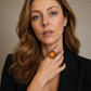 Woman wearing a large amber medieval statement ring on her finger against a neutral background