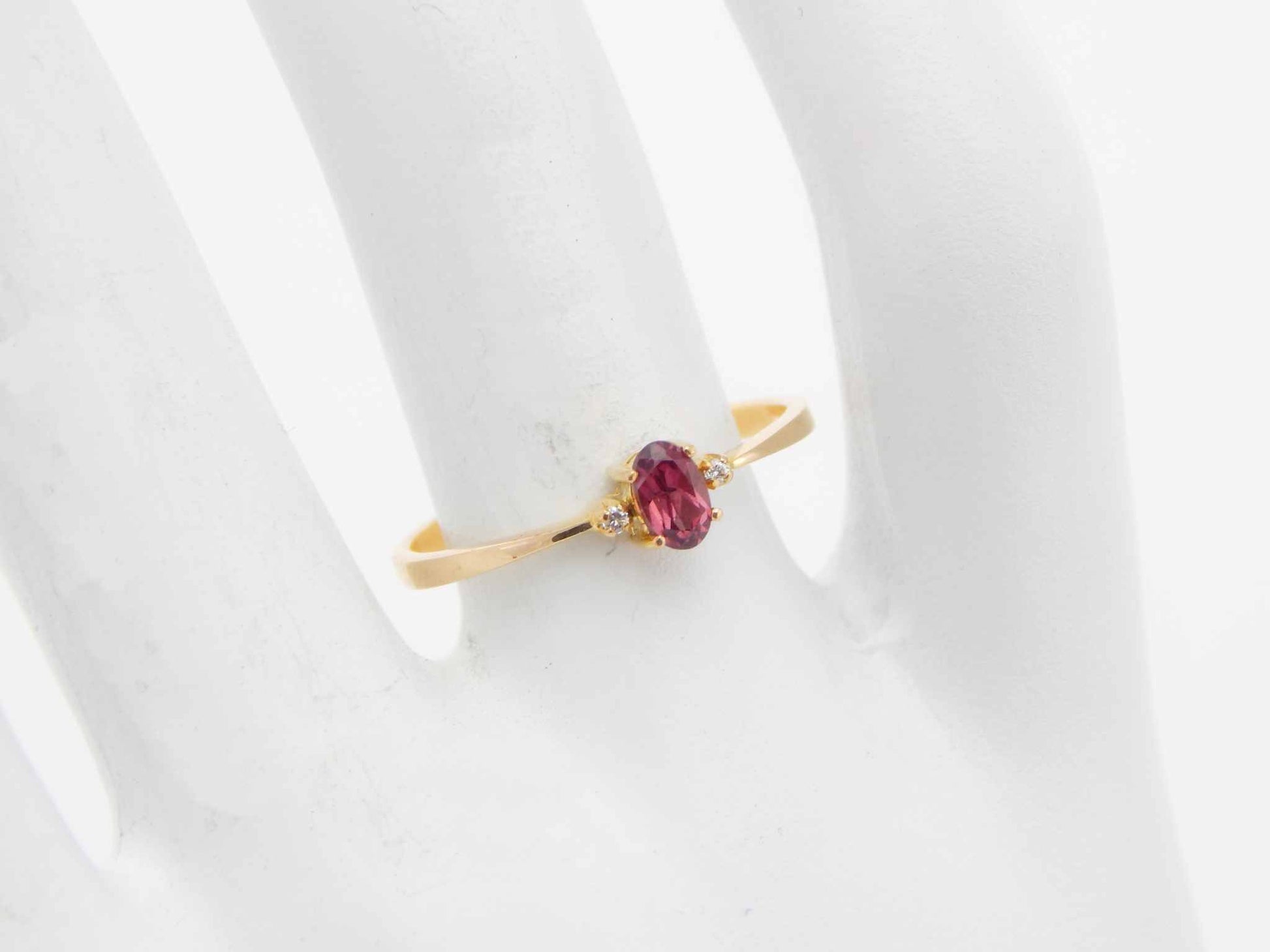 Genuine 14k gold ring with garnet and diamond on display.