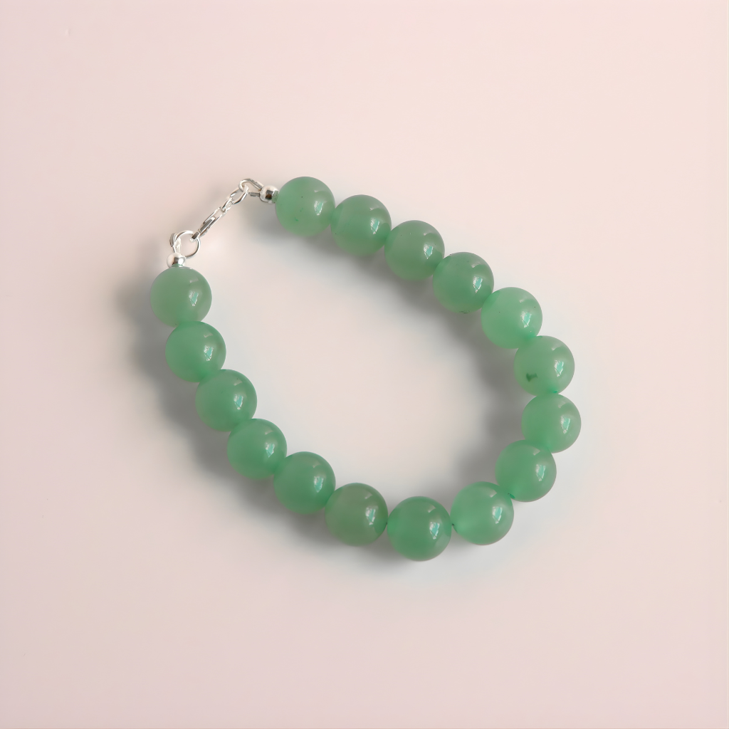 Green beaded jade bracelet on a light pink background