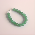 Green beaded jade bracelet on a light pink background