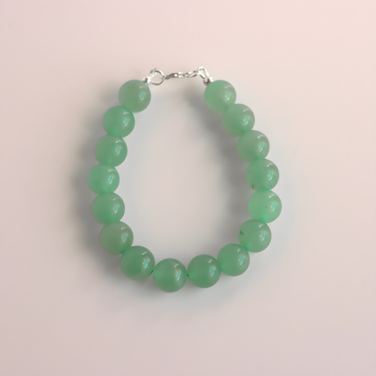 Green beaded jade bracelet on a light pink background