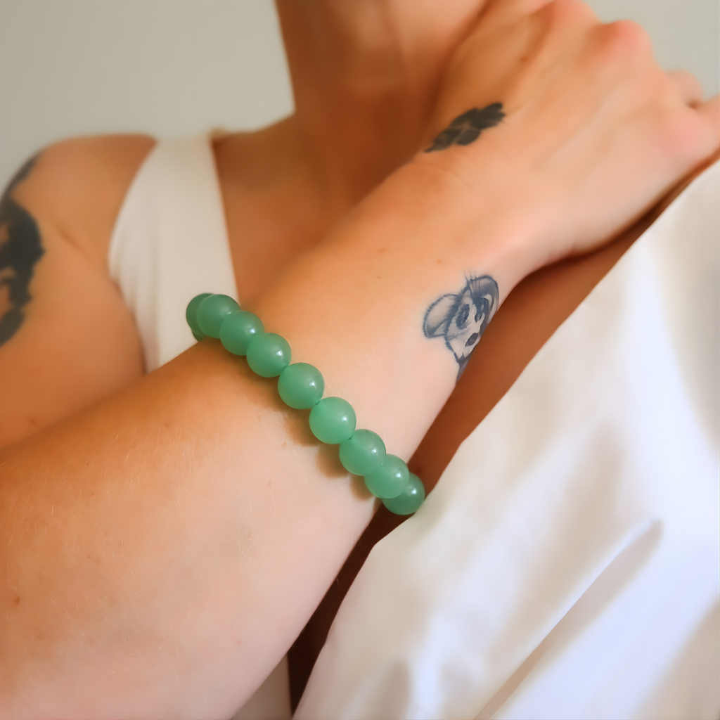 Green beaded jade bracelet on a wrist with tattoos visible