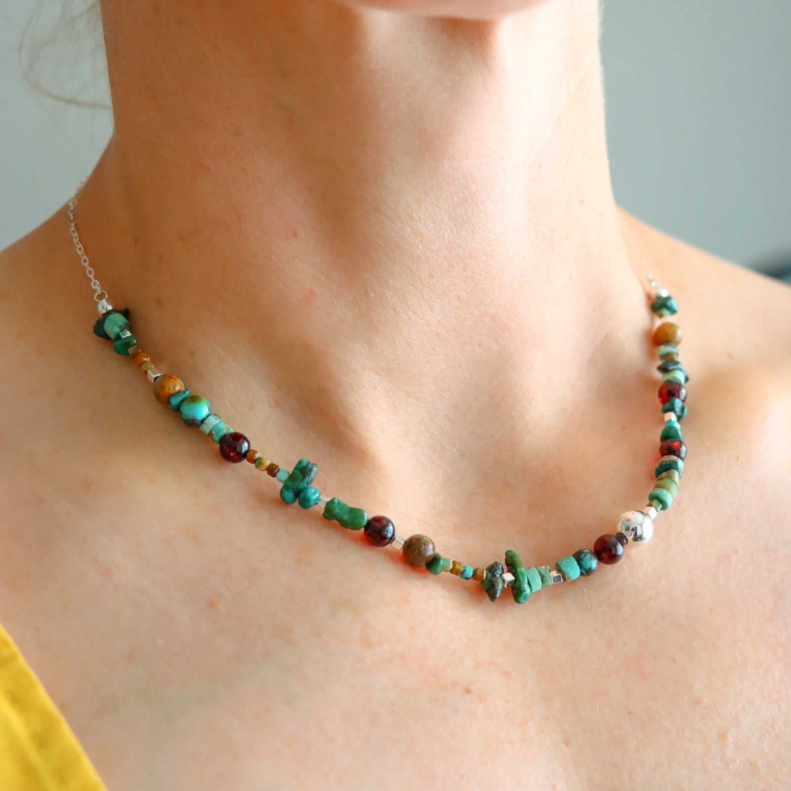 Turquoise beaded necklace with cherry amber and sterling silver on a woman's neck