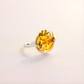 flower Ring with a yellow gemstone on a light pink background