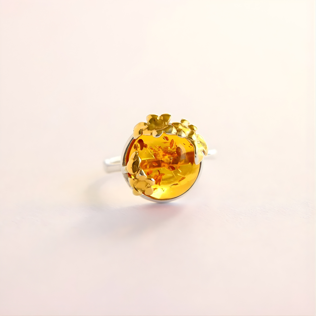 Gold flower ring with a large yellow gemstone on a light beige background
