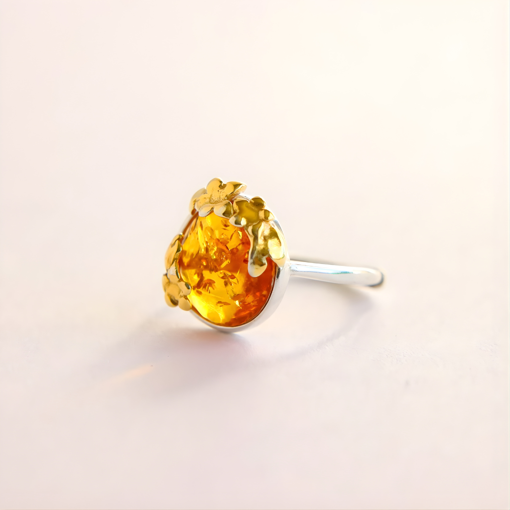 Gold and silver flower ring with a yellow gemstone on a light beige background