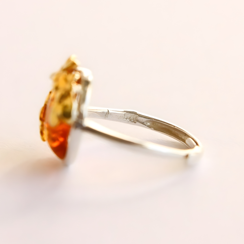 Gold flower ring with a large orange gemstone on a white background