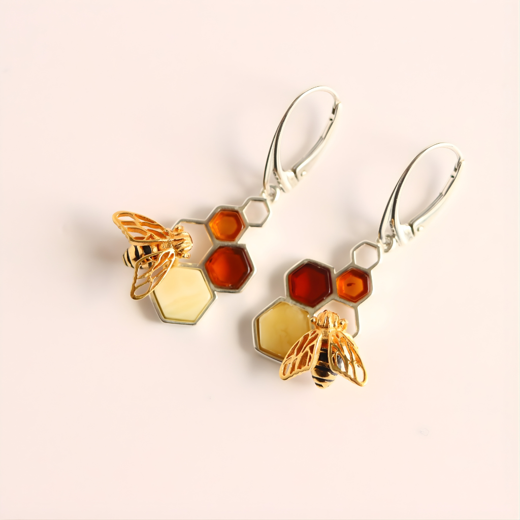 Pair of amber earrings with bee and honeycomb designs on a beige background