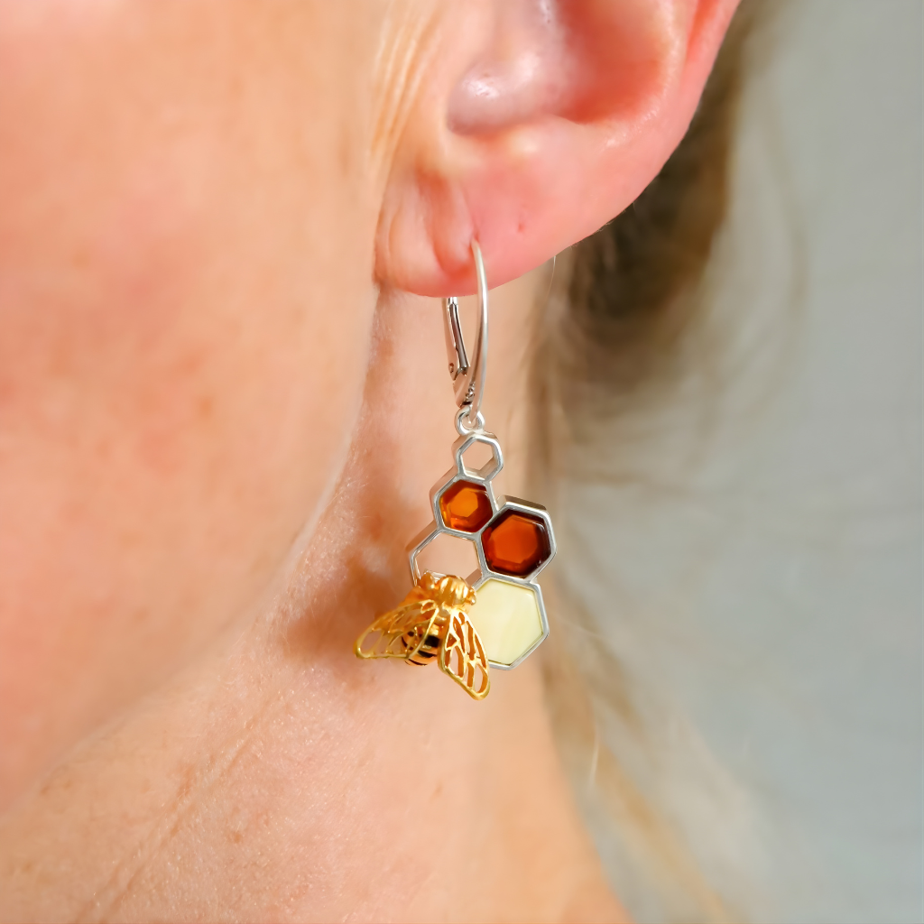 Close-up of a person wearing unique  amber earring with geometric designs.