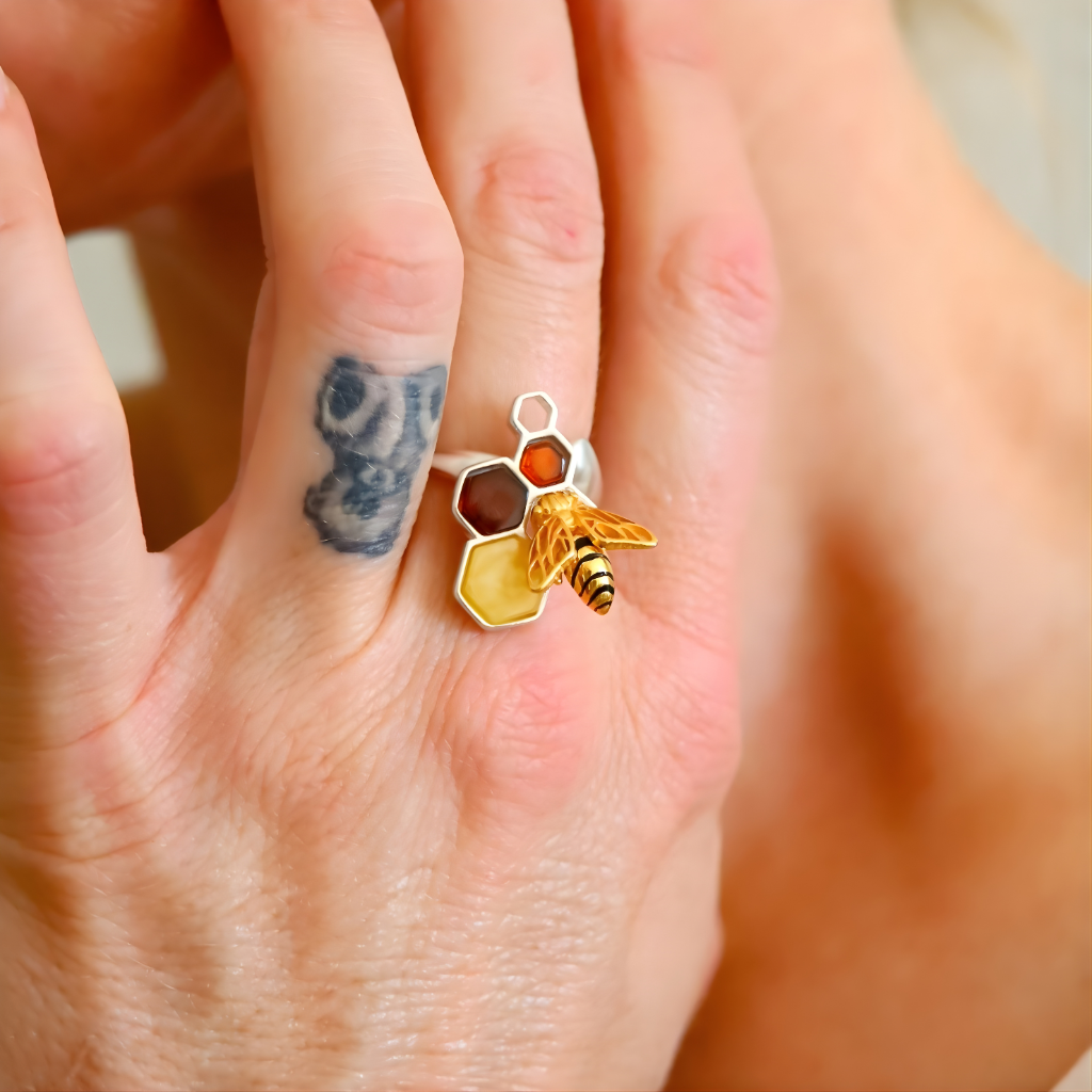 Close-up of a hand wearing a amber ring with a honeycomb and bee design.