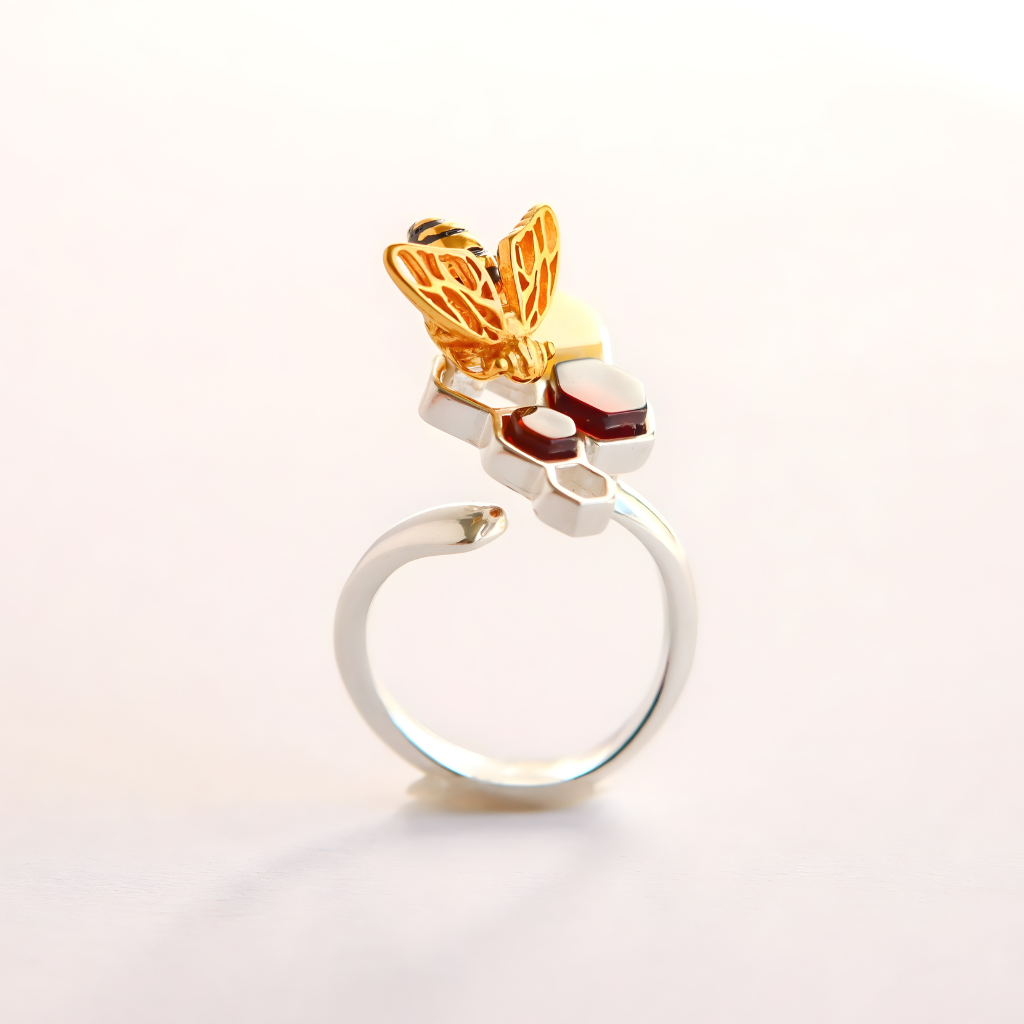 Gold and silver amber ring with honey bee design on a light gray background